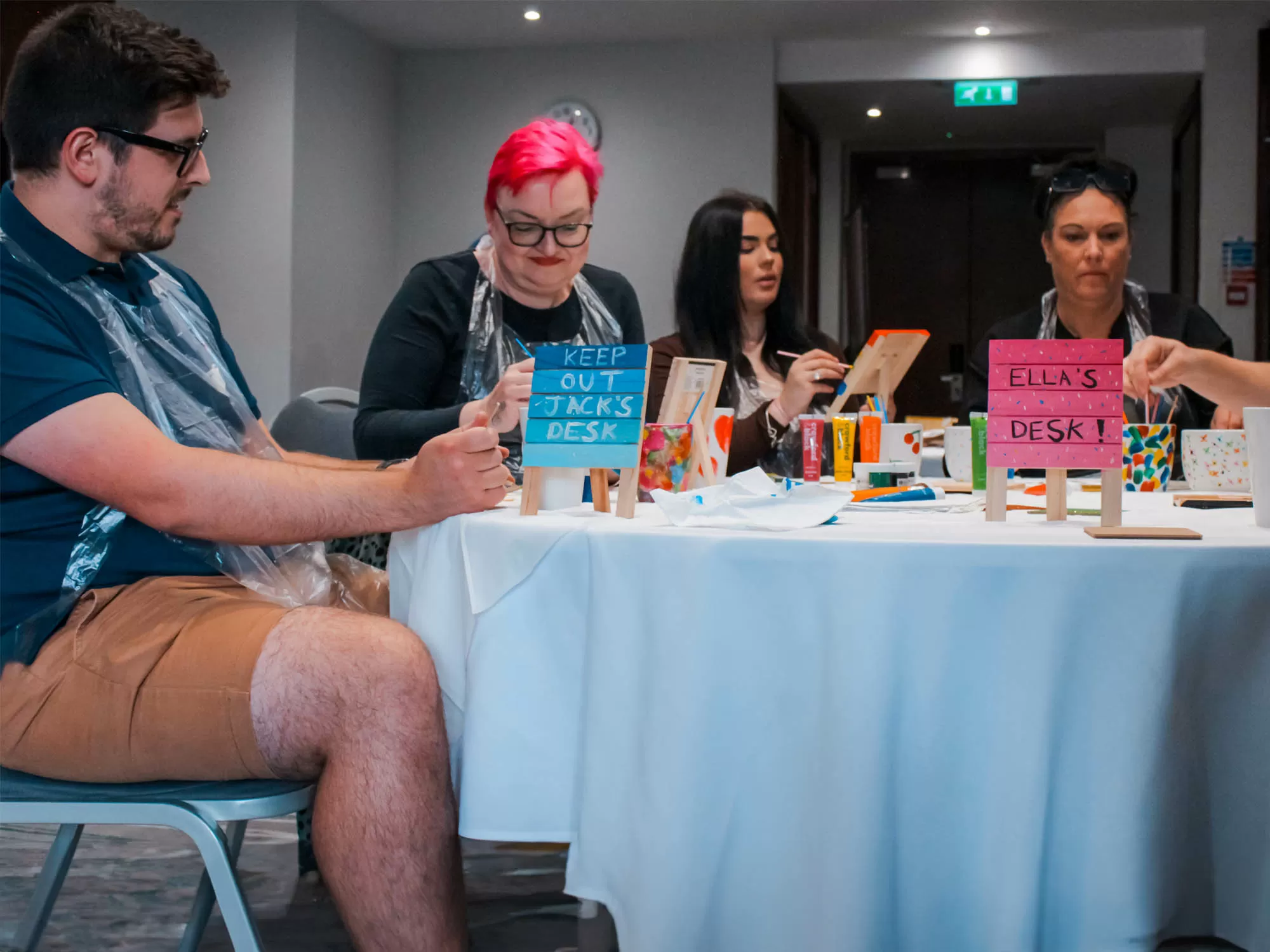Team customising coasters and mugs in a desk accessory painting class in Manchester